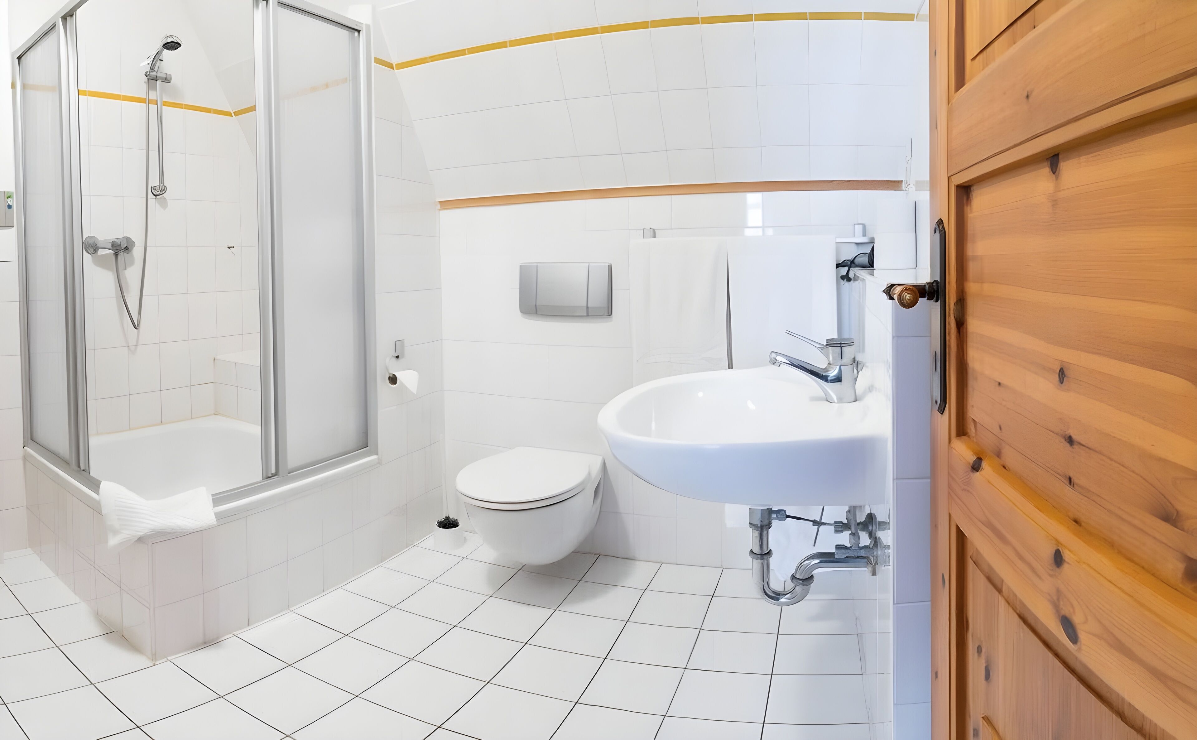 Ein modernes Badezimmer mit einer Duschkabine, einer weißen Toilette und einem Waschbecken mit Holztür.