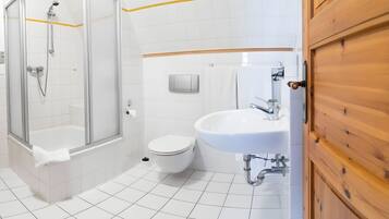 Ein modernes Badezimmer mit einer Duschkabine, einer weißen Toilette und einem Waschbecken mit Holztür.