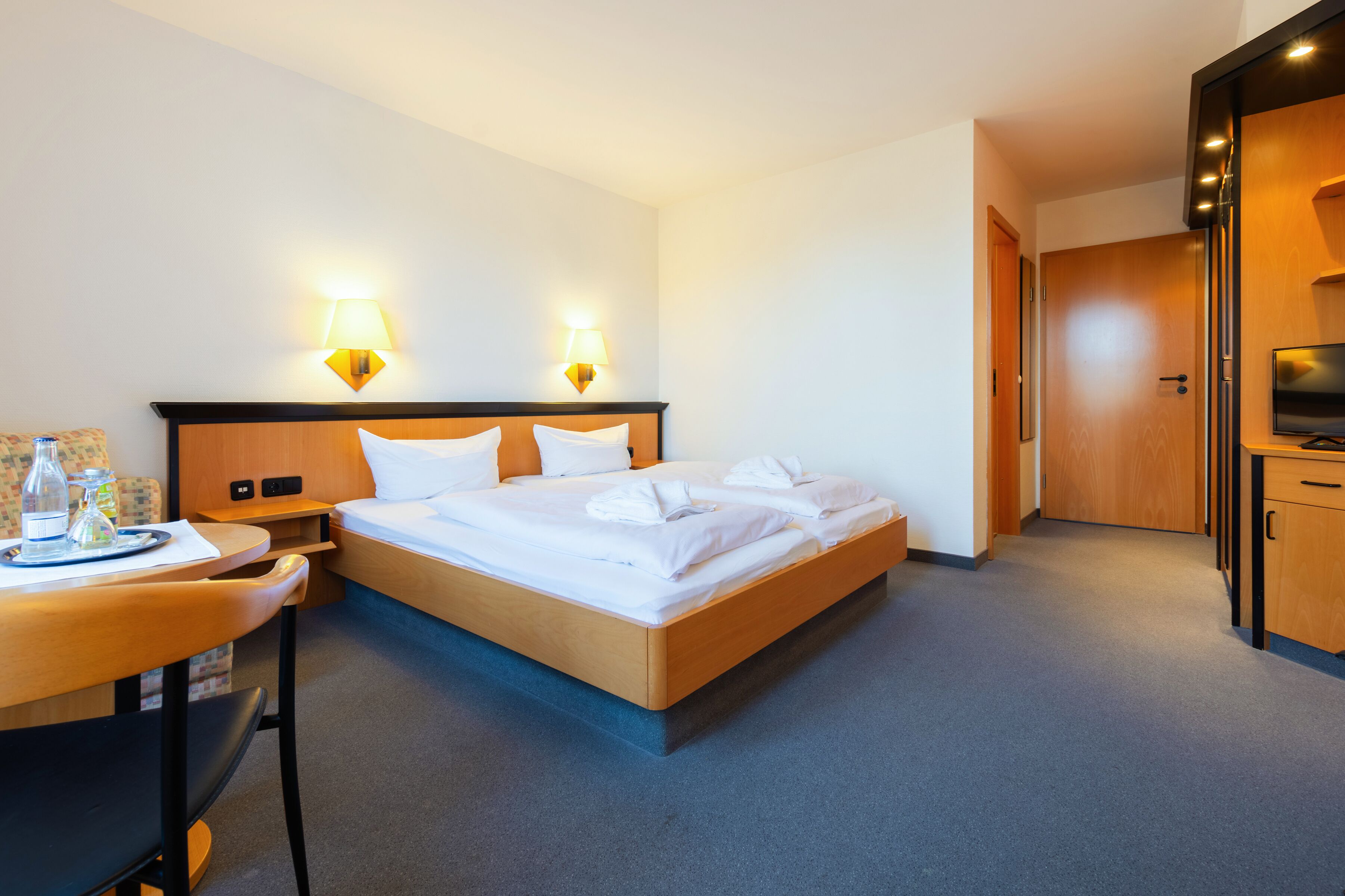 Una habitación de hotel con cama, mesitas de noche, escritorio y televisor.
