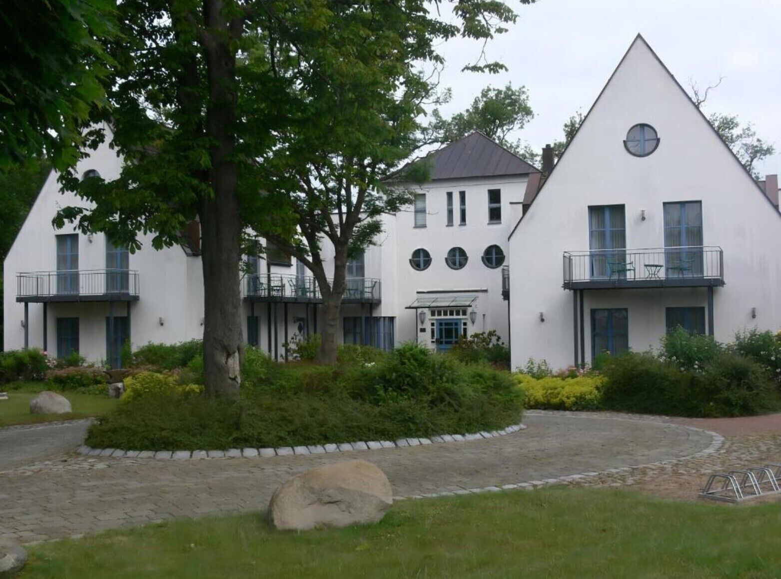 A white building with a triangular roof, multiple windows, and balconies.