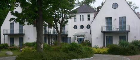A white building with a triangular roof, multiple windows, and balconies.