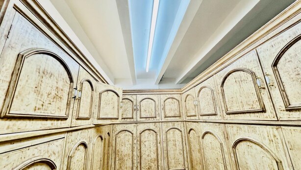A room with a high ceiling, arched doorways, and a central skylight.