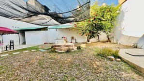 A courtyard with a fountain, a pergola, and a small garden area with pebbles and plants.