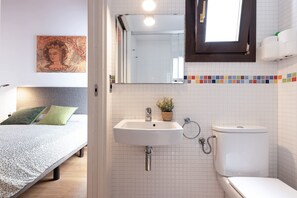 A bedroom with a bed, a bedside table, a nightstand, and a wall-mounted mirror. - Iconic Old Town - Unik Vacation (Tarragona)