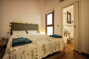 Un dormitorio con cama, mesita de noche y vistas al baño.