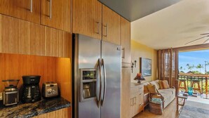 Eine moderne Küche mit Holzausstattung, einem Edelstahlkühlschrank, einer Kaffeemaschine und einem Toaster.