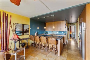 A modern kitchen with a central island, bar stools, and a dining table.