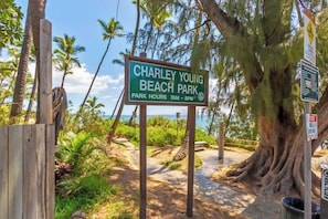 A sign for Charley Young Beach Park with park hours listed.