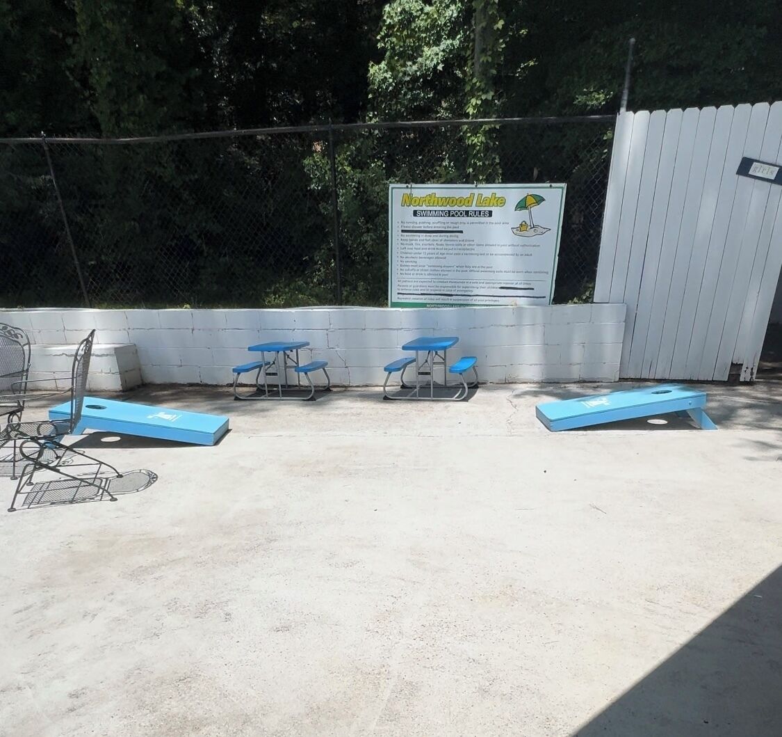 Zona de piscina al aire libre con bancos azules y un cartel que detalla las normas de la piscina.