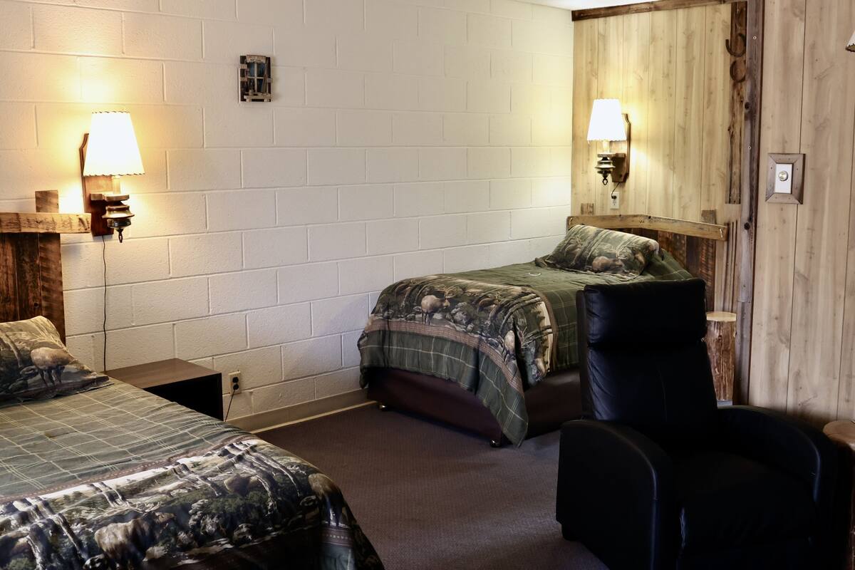 Een kamer met twee bedden, een stoel en twee wandlampen.