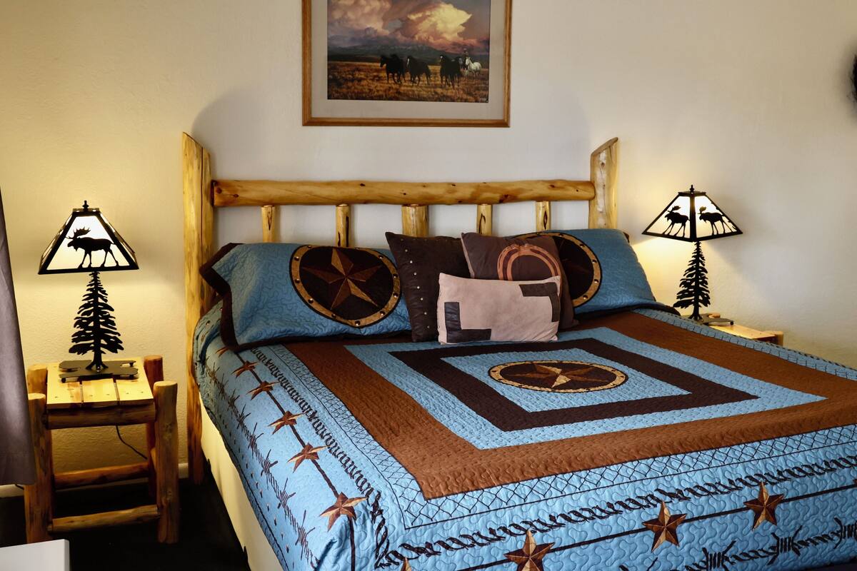 Een bed met een gewatteerd deken, een houten hoofdbord en twee bedlampjes.