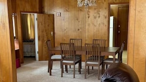 A dining room with a wooden table and chairs, a chandelier, and a carpeted floor. - Walk to the Mercantile, downtown, Osage Nation offices, Osage Tribal Museum! (Pawhuska)