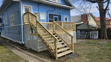 Una casa de dos pisos con una escalera de madera que sube a un porche.