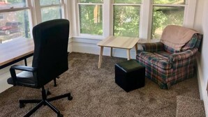 A room with a black office chair, a plaid armchair, a small wooden table, and a black ottoman. - Walk to the Mercantile, downtown, Osage Nation offices, Osage Tribal Museum! (Pawhuska)