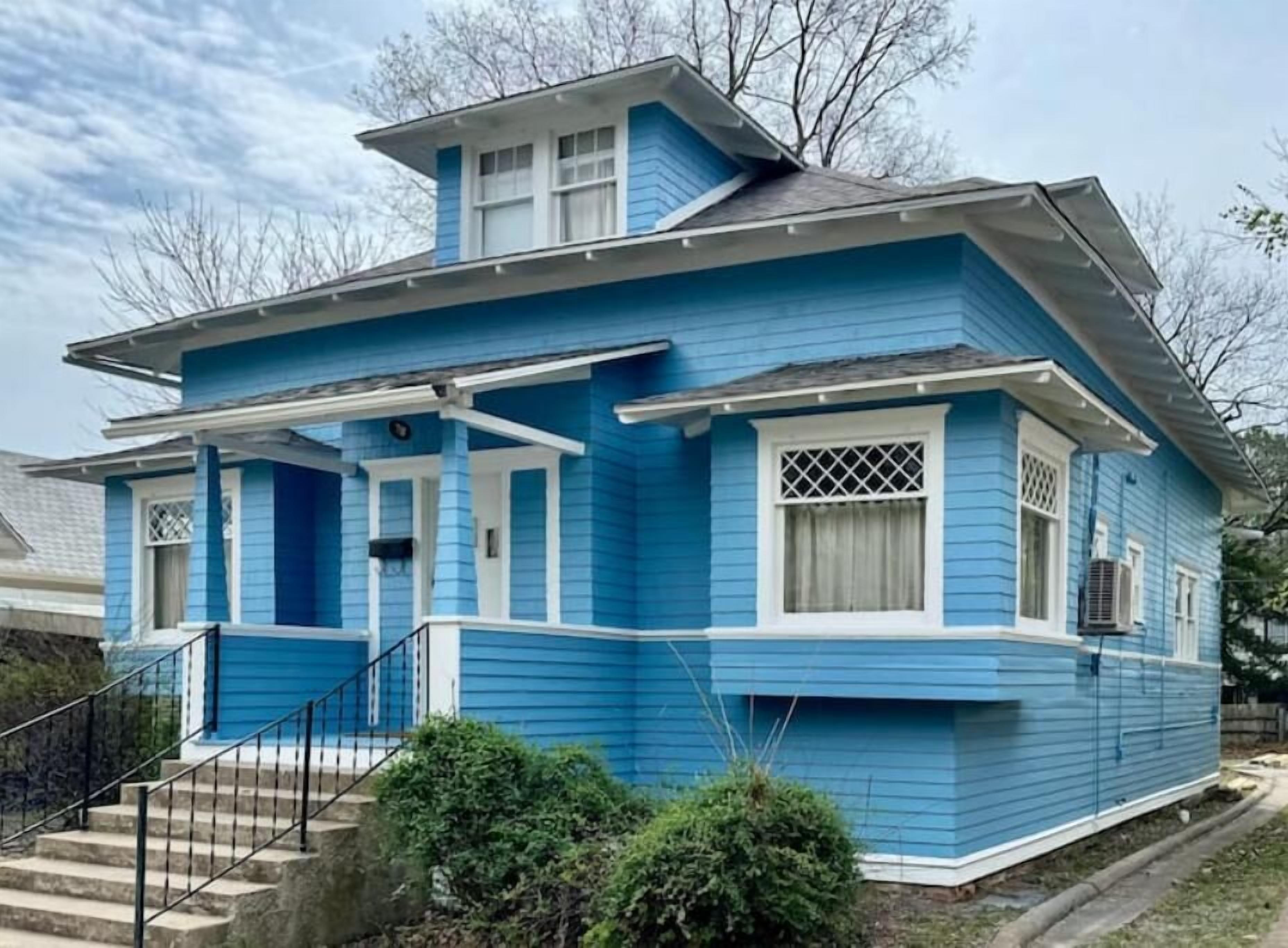 Een blauw huis met een veranda, een kleine trap en een garage.