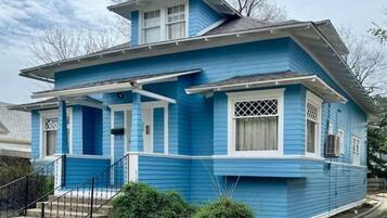 Een blauw huis met een veranda, een kleine trap en een garage.