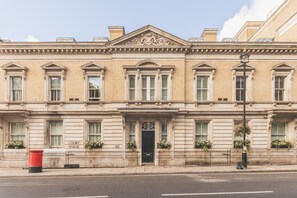 Un edificio clásico con fachada simétrica, una entrada central con puerta negra y el número 165 sobre la puerta.