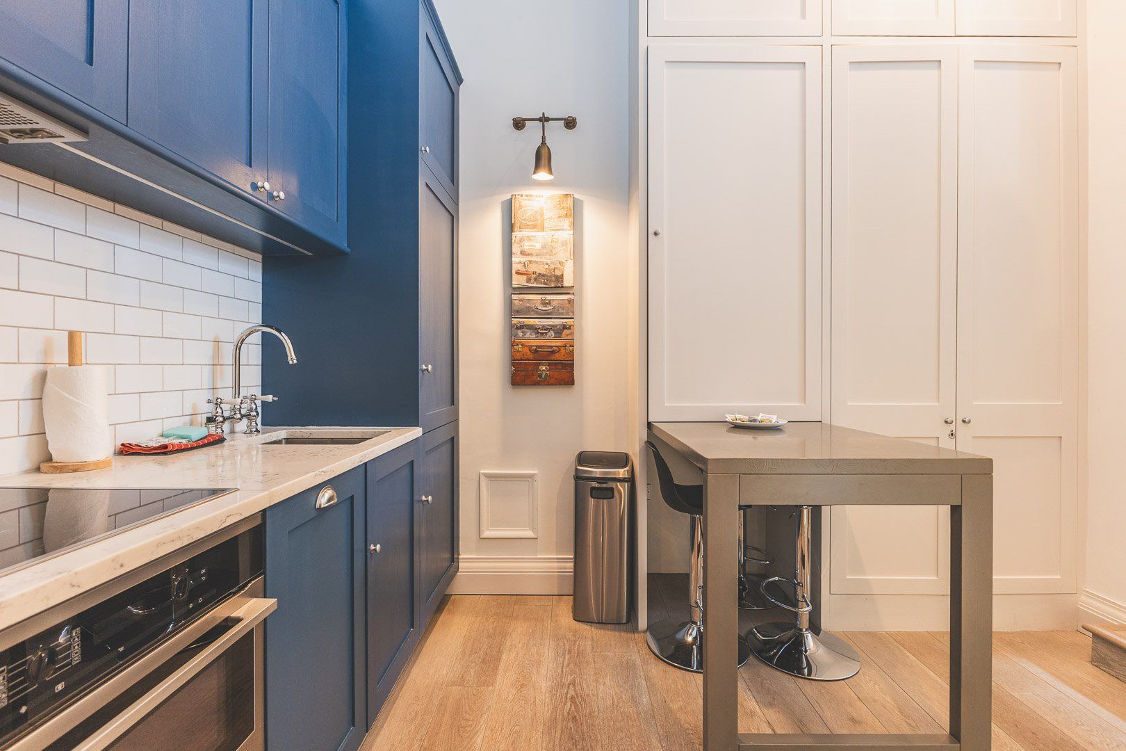A kitchen with blue cabinets, a stainless steel sink, and a wooden countertop.