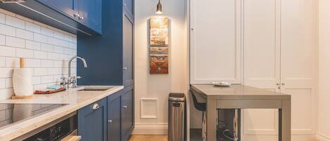 A kitchen with blue cabinets, a stainless steel sink, and a wooden countertop.