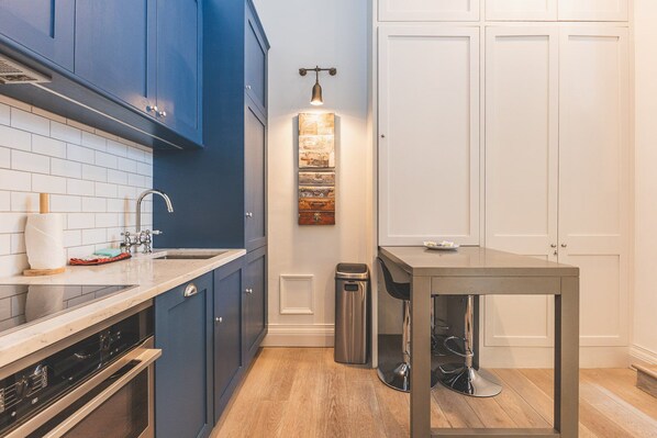 Una cocina con armarios azules, un lavamanos de acero inoxidable y una encimera de madera.