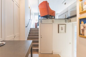 Una escalera conduce a un segundo piso, con una moderna silla naranja en una plataforma.