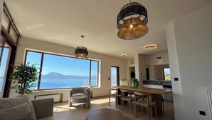 Een moderne woonkamer met een groot raam, een eethoek en een keuken.