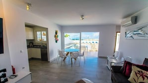 A modern apartment with a kitchen, dining area, and a balcony with a pool view. - Casa Bill - Firepit Nights by Villas Now (Playa Blanca)