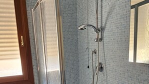 Une salle de bain avec une douche à parois de verre, des toilettes blanches, un lavabo bleu et un miroir.