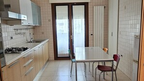 Une cuisine moderne avec un coin repas, comprenant un îlot central, des placards et une vue à travers la porte vitrée.