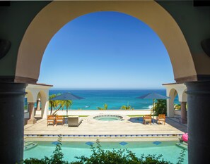 A poolside view with a clear view of the ocean, lounge chairs, umbrellas, and a circular hot tub. - Amazing Hacienda-style Ocean Front Villa w/private beach palapa. (San José del Cabo)