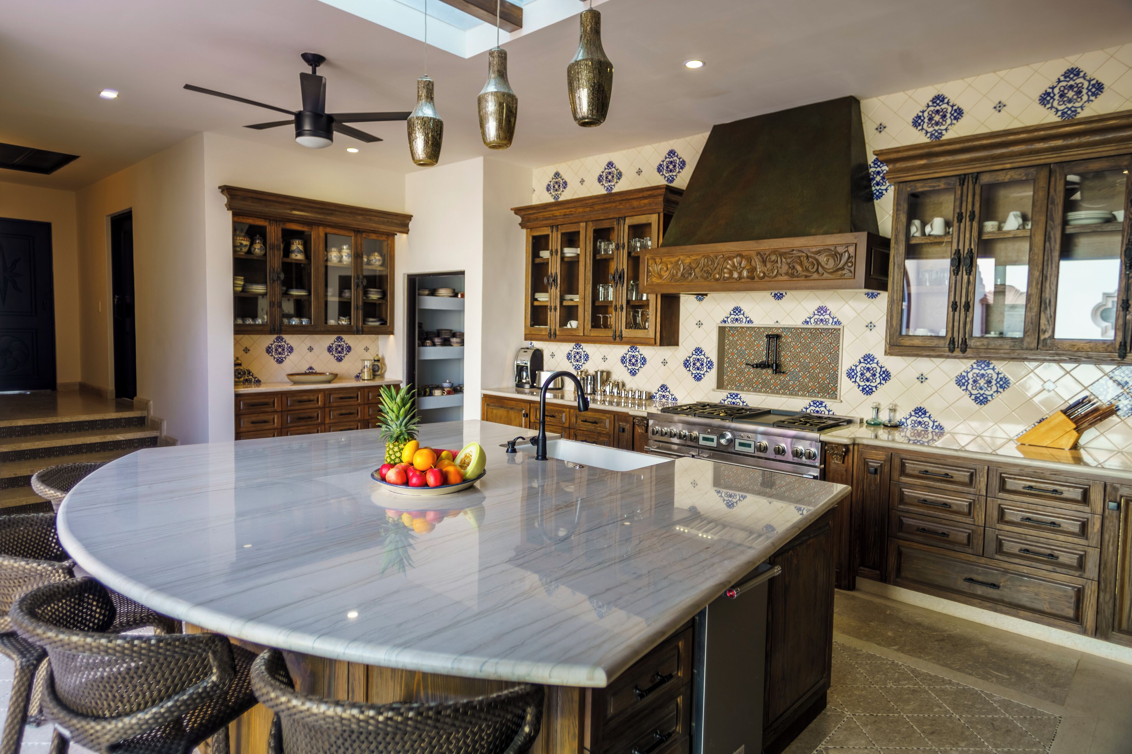Une cuisine dotée d’un îlot central, de meubles en bois et d’un dosseret aux motifs bleus et blancs.