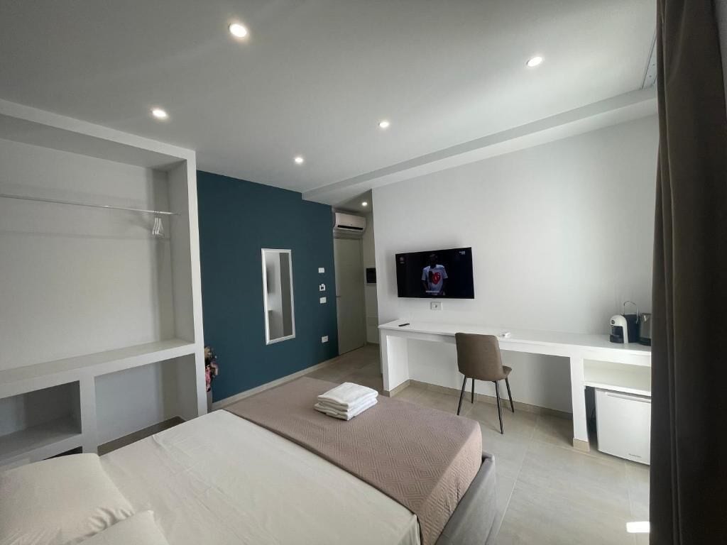 Een moderne hotelkamer met een bed, een bureau, een stoel, een televisie en een kledingkast.
