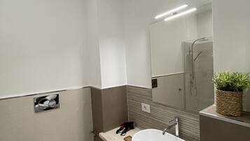 Une salle de bain moderne avec des toilettes blanches, un grand lavabo et une douche.