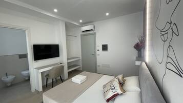 Una habitación de hotel moderna con cama, escritorio, televisor y baño.