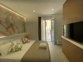 Une chambre d’hôtel moderne dotée d’un grand lit, d’une télévision à écran plat et d’un balcon offrant une vue sur l’extérieur.