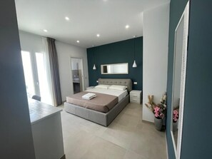 Ein modernes Schlafzimmer mit Bett, Nachttischen, einem Spiegel und einem Fenster mit Vorhängen.