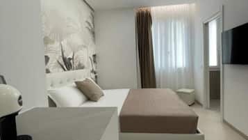 A modern bedroom with a bed, bedside table, and a flat-screen TV mounted on the wall.