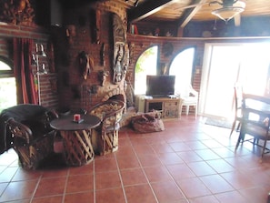 Cozy retreat with a brick fireplace, television, wicker chair, and candlelit table.
