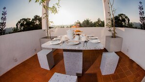 A dining table set outdoors with white plates, cups, and a teapot. - Golden Shower Inn (Kandy)
