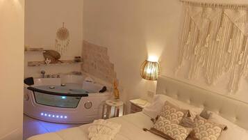 A spacious bedroom with a large bed, a jacuzzi, and a wall-mounted macrame piece.