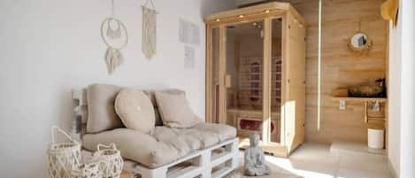 A cozy room with a sofa, a small table with lanterns, a wooden cabinet, and a meditation statue.