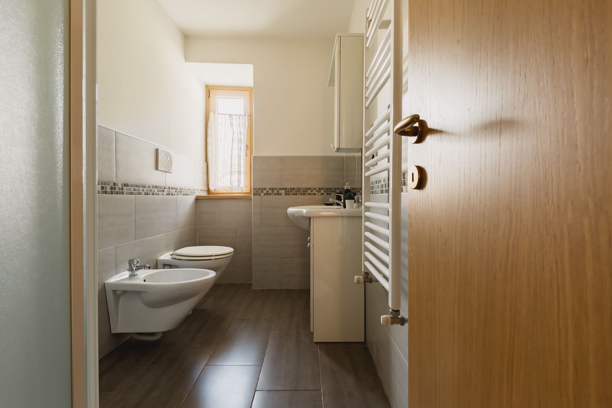 A compact bathroom with a toilet, bidet, and sink.
