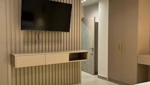 Un dormitorio moderno con una cama grande, un televisor montado en la pared y un armario.