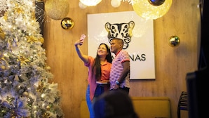 Un espacio interior decorado con un árbol de Navidad, una pared de madera y un cartel con un logotipo.