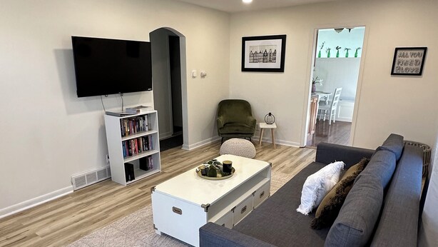 A modern living room with a grey sofa, a white coffee table, and a bookshelf.