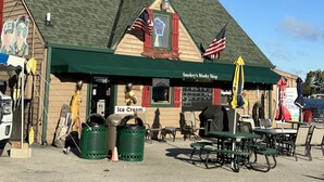 A building with a green awning, an American flag, and a sign for 'Smokey's Musky Shop'.