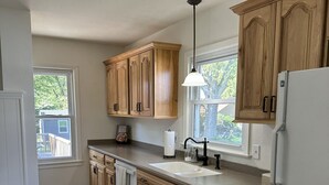 A modern kitchen with wooden cabinets, a white refrigerator, and a window providing natural light.
