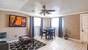 A living room with a ceiling fan, a dining table with chairs, a sofa, and a coffee table. - Perfect home away from home. Excellent weekend getaway. (Houston)