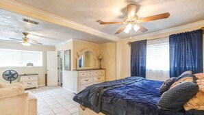 A bedroom with a large bed, two ceiling fans, a dresser, a mirror, and a window with curtains. - Perfect home away from home. Excellent weekend getaway. (Houston)