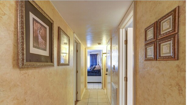 A hallway with framed pictures on the walls, a bed in the background, and a door on the right. - Perfect home away from home. Excellent weekend getaway. (Houston)